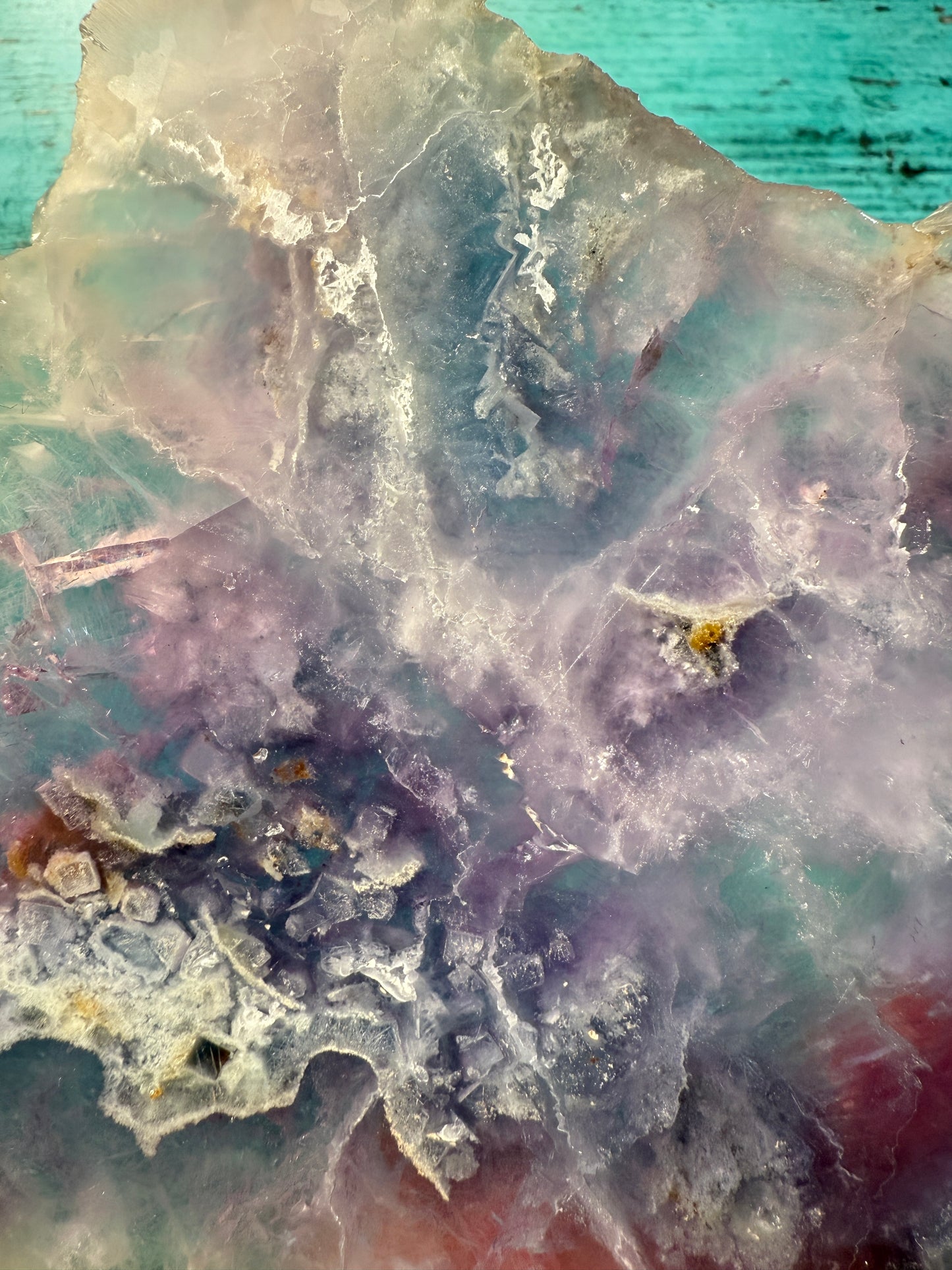 Pink, purple, and blue Fluorite crystal slab on a modern black stand, used as elegant home decor