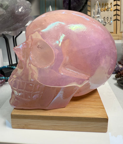 Large Pink Aura Rose Quartz crystal skull, measuring approximately 5 x 5.5 inches and weighing 4 lbs. Features soft pink coloration and a glowing, iridescent surface. Displayed as a carved decorative stone with heart-focused elegance.