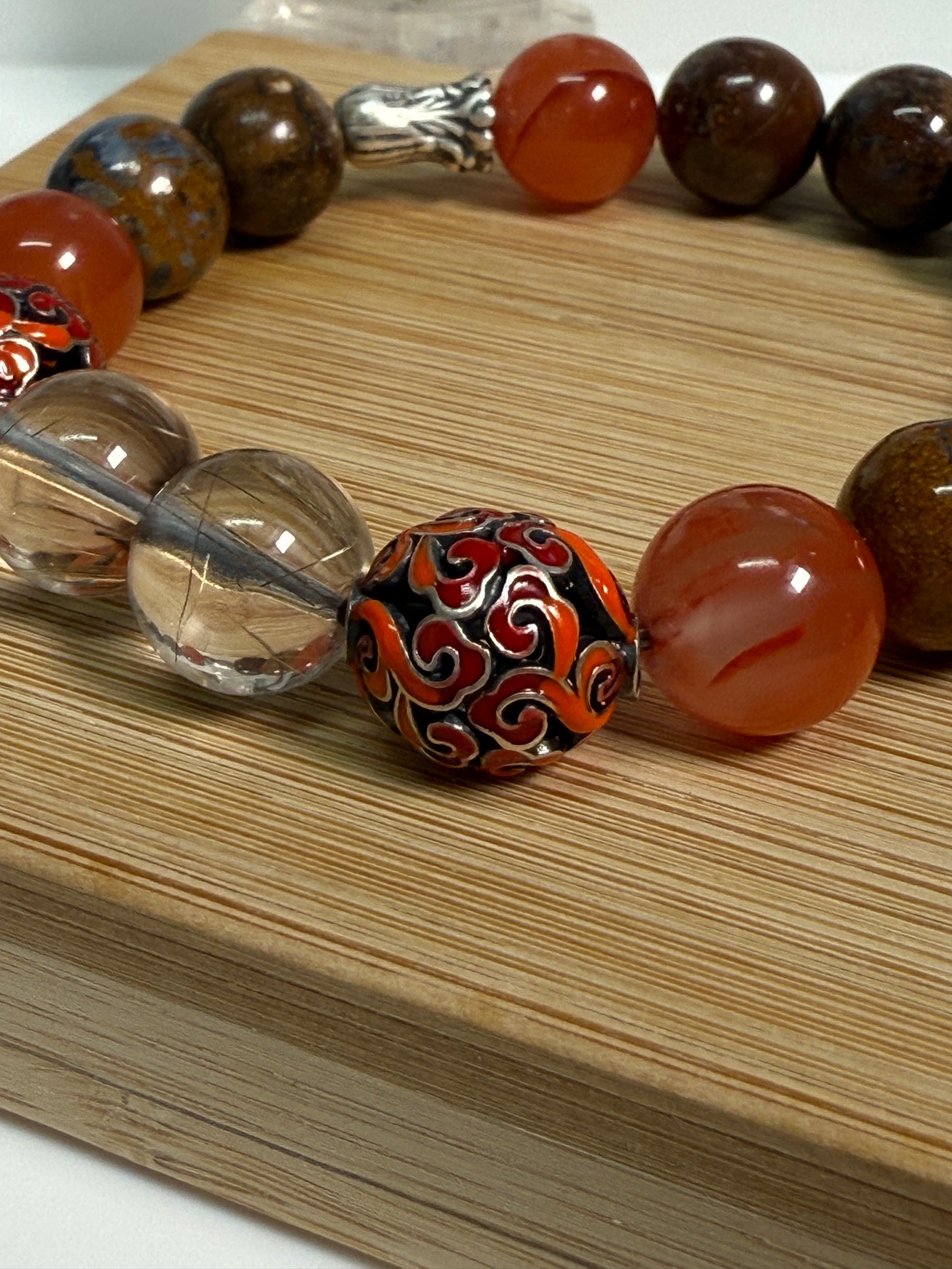 Crystal bracelet featuring South Red Agate, Pietersite, Rutile-in-Quartz, and Brown Opal, with 925 sterling silver cabbage and enameled beads, accented by a clear quartz ring. A sculptural fine jewelry piece symbolizing growth, clarity, and inner resilience.