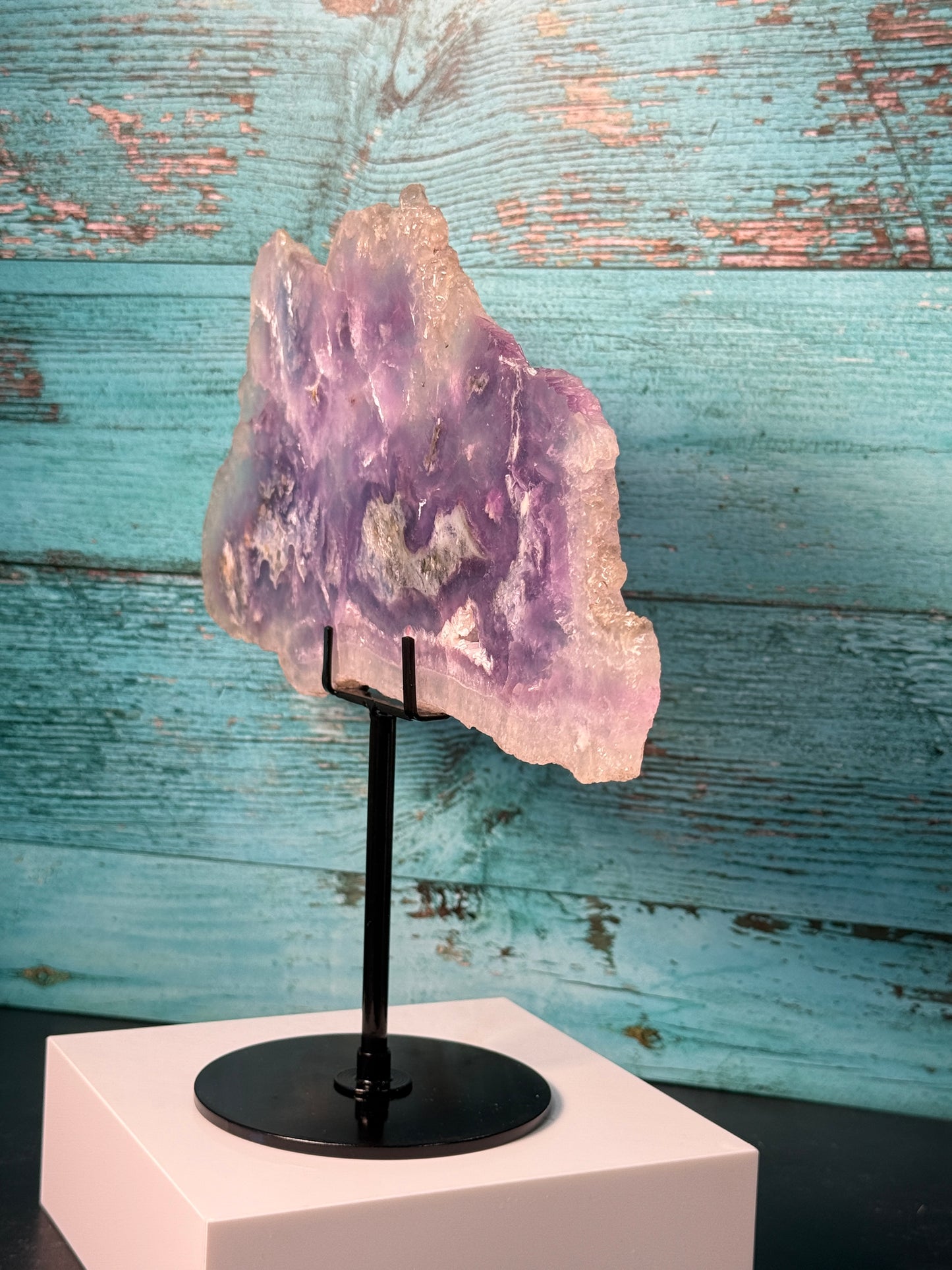 Pink, purple, and blue Fluorite crystal slab on a modern black stand, used as elegant home decor