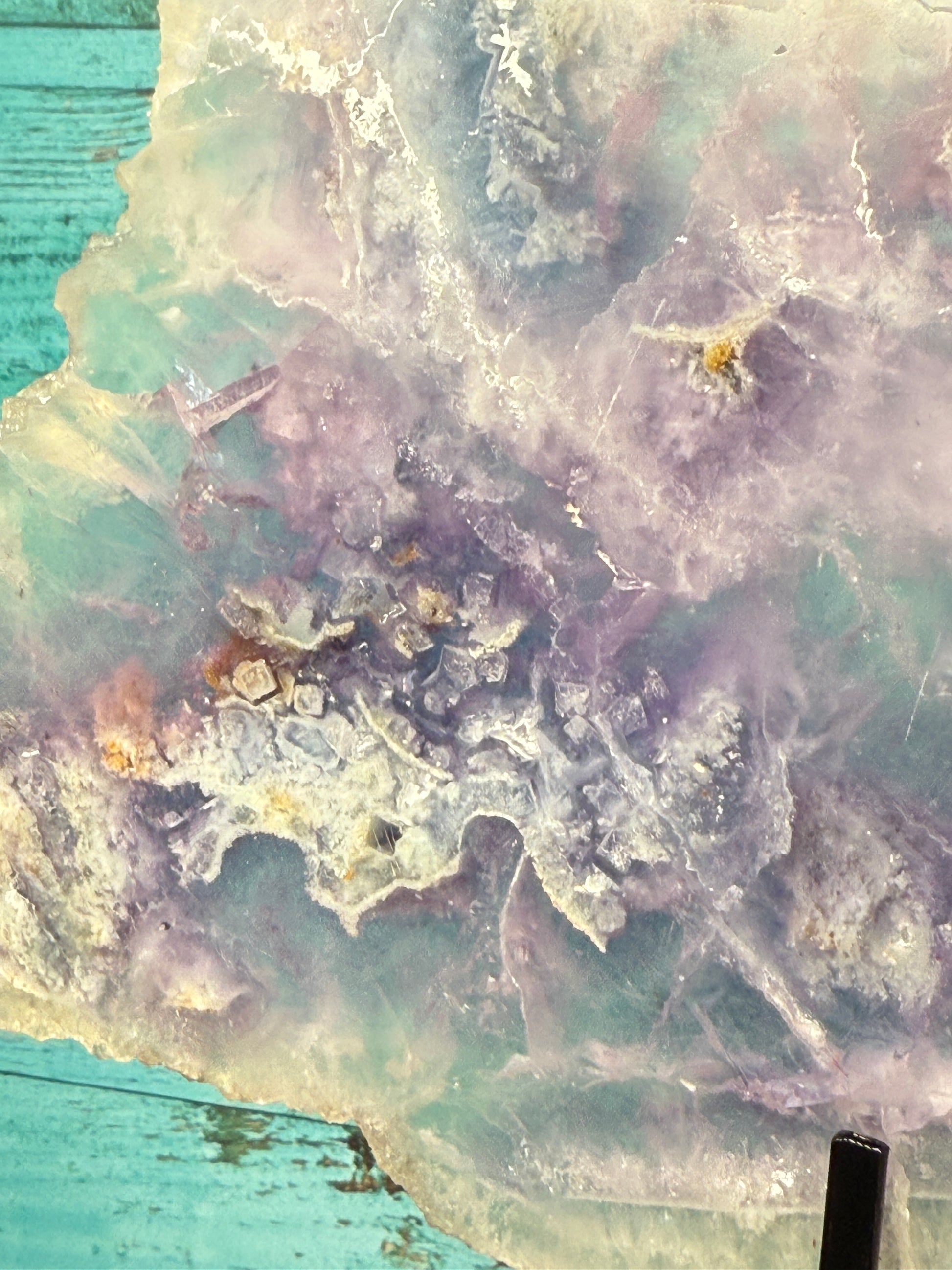 Pink, purple, and blue Fluorite crystal slab on a modern black stand, used as elegant home decor