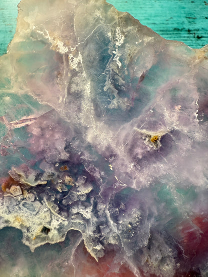 Pink, purple, and blue Fluorite crystal slab on a modern black stand, used as elegant home decor